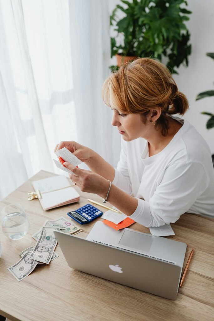 Woman Counting Money and Using Laptop 